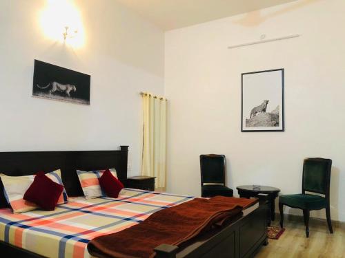 a bedroom with a bed and two chairs at Jawai Leopard Villa in Bijāpur
