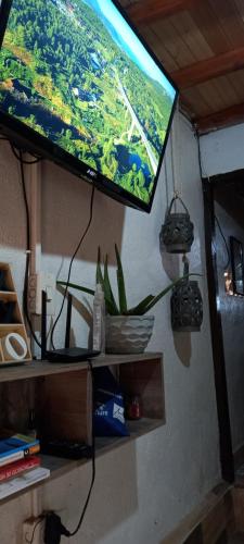 a flat screen tv hanging from a wall at Boresta House -Santa Elena con vista al Bosque y terraza privada in Medellín