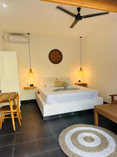 a bedroom with a large white bed and a table at Santai Retreat in Kuta Lombok