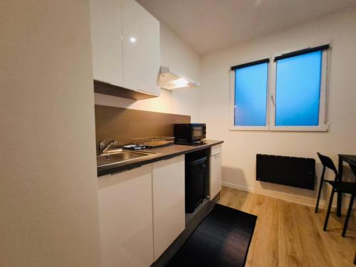 une cuisine avec des armoires blanches, un évier et une fenêtre dans l'établissement Studio Cosy Métro 14 Paris, à Orly