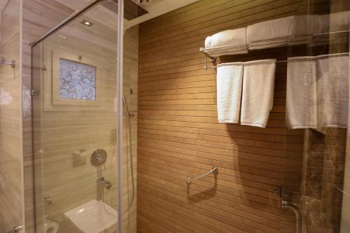a bathroom with a shower and a toilet and towels at Cairo Taj Hotels & Suites- Mohandessin in Cairo