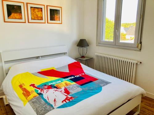 a bed with a colorful quilt on it in a bedroom at Vitamine Sea in Ploemeur