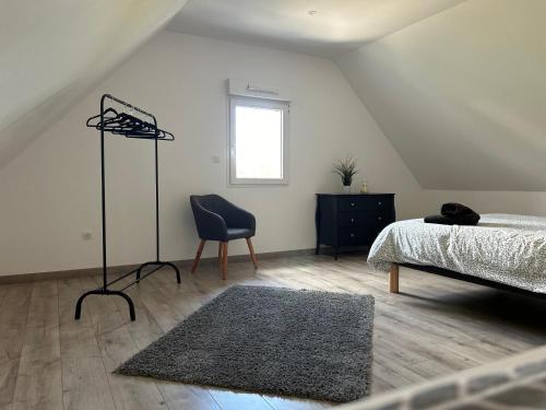 une chambre avec un lit, une chaise et une fenêtre dans l'établissement Gîte neuf en duplex tout confort, à Ribeauvillé