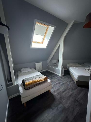 - une chambre mansardée avec 2 lits et une fenêtre dans l'établissement Les Champs De La Mer, à Auberville-la-Renault