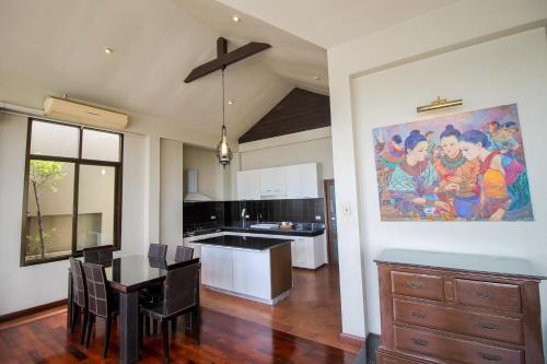 a kitchen with a dining table and a painting on the wall at Sourire at Rattanakosin Island Hotel in Bangkok