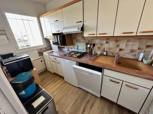 une petite cuisine avec des armoires blanches et un évier dans l'établissement Plein Soleil, Appartement 2 chambres, Balcon et vue mer, à Villers-sur-Mer