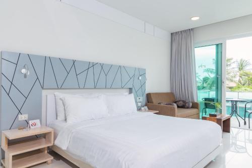 a bedroom with a large white bed and a balcony at KC Beach Club & Pool Villas in Chaweng