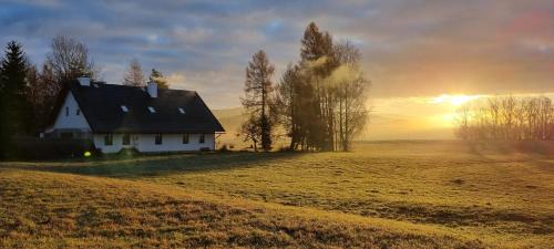 a house on a field with the sunset in the background at HabaChalupa in Šumperk