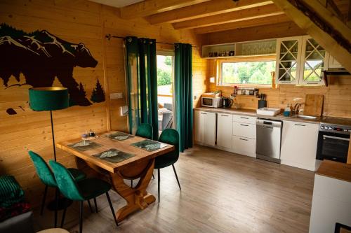a kitchen with a table and some green chairs at Domki u Niedźwiadka in Wola Sękowa