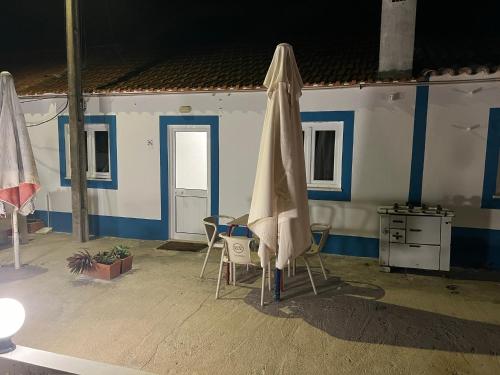 a patio with a table and a umbrella and chairs at ESTANQUEIRA GUEST HOUSE in Sines