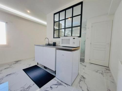 a white kitchen with a microwave on a counter at Studio spacieux Métro 14 Paris in Orly
