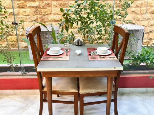 a wooden table with two chairs and a table with plates and dishes at Reef House in Marsa Alam City