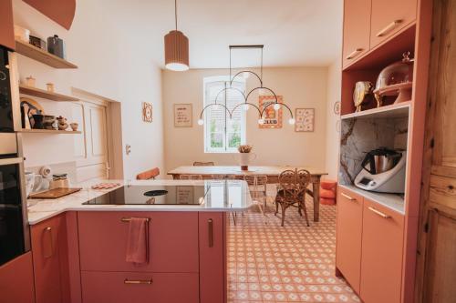 une cuisine avec des placards rouges et une salle à manger dans l'établissement La Maison Trèfle - Entre terre et mer - 3 chambres et 4 lits double, à Kerlouan