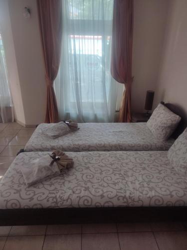 two beds sitting in a room with a window at Guest House Best Food in Subotica