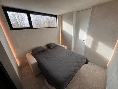 a small bedroom with a bed and a window at The Box in Sint-Pieters-Leeuw