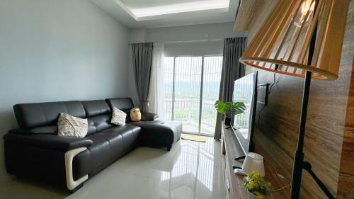 a living room with a black leather couch and a window at IPOH Sky Garden Residences, 31200 Chemor Ipoh in Chemor