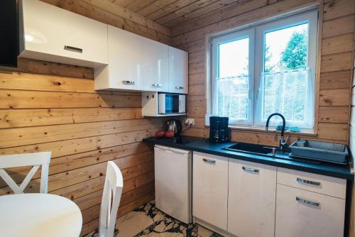a kitchen with white cabinets and a sink and a window at Perłowe Wzgórze in Ustronie Morskie