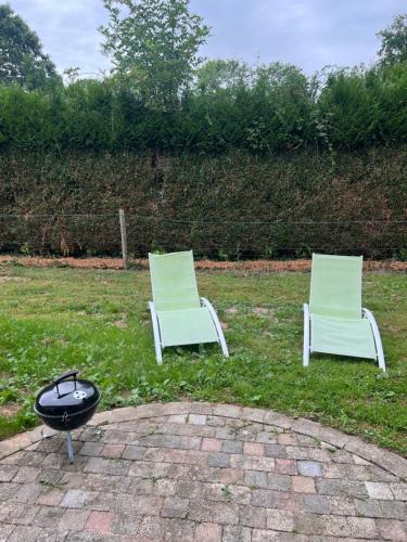 two white chairs and a grill in the grass at Un peu de campagne in Saint-Gilles-de-la-Neuville