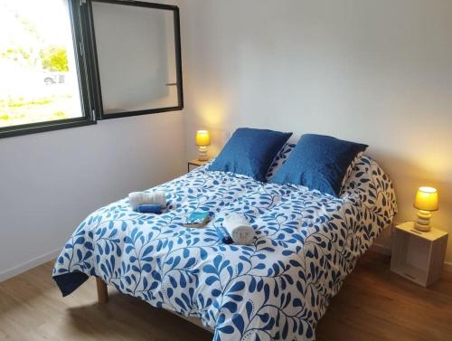 - un lit avec des draps bleus et blancs et des oreillers bleus dans l'établissement Maison familiale, confortable, au coeur du village, à Taulé