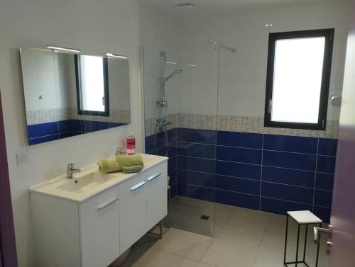 une salle de bain avec un lavabo et une douche avec du carrelage bleu dans l'établissement Maison familiale, confortable, au coeur du village, à Taulé
