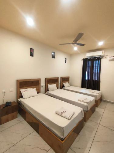 a room with three beds and a ceiling at Srirathna Temple View Inn in Thanjāvūr