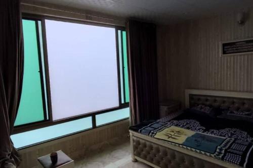 a bedroom with a bed and a large window at House of views in Retri Gali