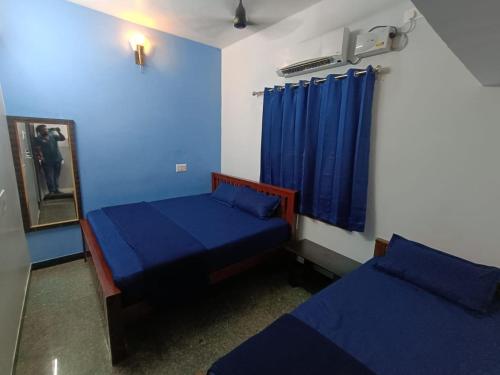 two beds in a room with blue walls at Omkara - The Fives Guest house in Tiruvannāmalai