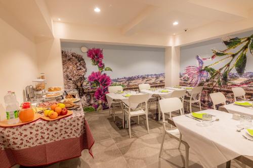 a restaurant with white tables and chairs and a painting at Profumi di Primavera Luxury Rooms & Suite in Matera