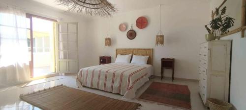 a white bedroom with a bed and a window at Appartement lumineux à Tanger avec grande terrasse in Tangier