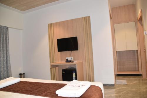 a hotel room with a bed and a flat screen tv at Hotel Aarush Inn in Navi Mumbai