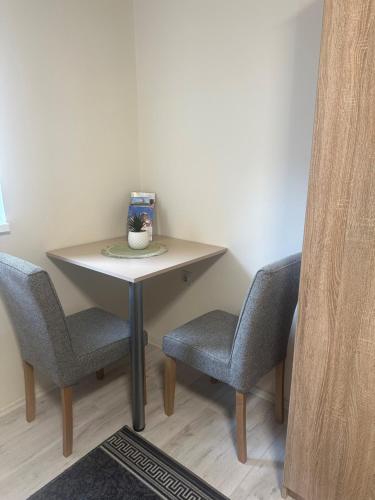 a small table with two chairs and a vase on it at Sobe Tanja in Subotica