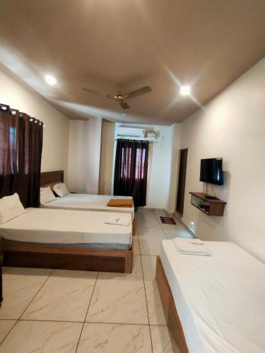 a hotel room with two beds and a tv at Srirathna Temple View Inn in Thanjāvūr