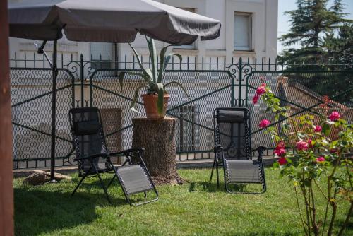 three chairs and an umbrella in front of a fence at ByVigin in Magliano Alfieri
