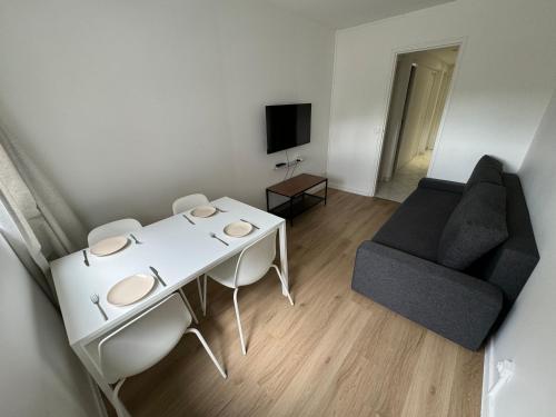 un salon avec une table blanche et un canapé dans l'établissement Studio Grigny, à Grigny