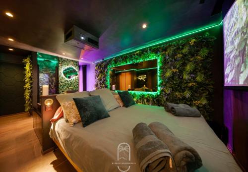 une chambre avec un grand lit avec un mur végétal dans l'établissement Jungle Love Room Balnéo/cinéma By HC, à Hyères