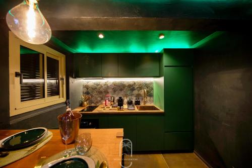 une cuisine avec des placards verts et une table en bois dans l'établissement Jungle Love Room Balnéo/cinéma By HC, à Hyères