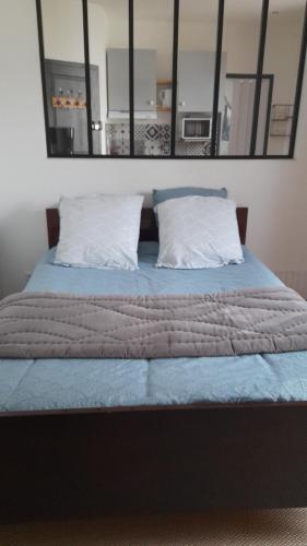 - un lit avec des draps bleus et 2 oreillers dans l'établissement Studio cosy proche de Paris et Orly, à Ville Héry