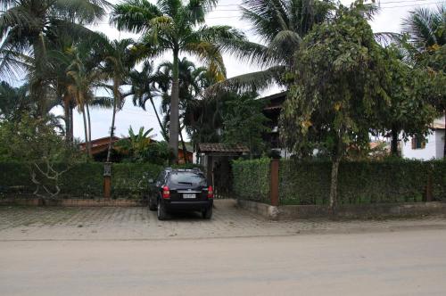 a car parked in front of a house with palm trees at Pousada Chalé Suíço in Paraty