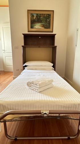 a bed with a wooden headboard with a towel on it at Pang's Home in Marghera