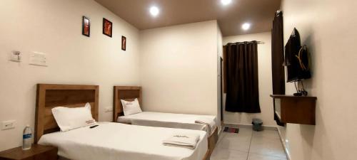 a small room with two beds and a television at Srirathna Temple View Inn in Thanjāvūr