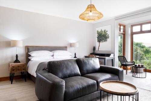 una camera con letto e divano in pelle di Avemore Manor House wood fired hot tub magical views and full Backup power a Stellenbosch