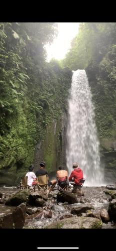 three people sitting in chairs in front of a waterfall at Farmer homestay in Tetebatu