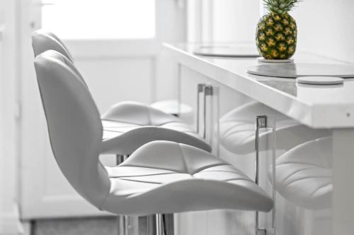 a row of white chairs at a table with a pineapple at Witton Lodge 3 Bedroom House - Long Stay Offers in Birmingham