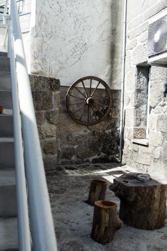 a stone wall with a wheel on the side of a building at Casa dos Chuchos in Cabanas de Viriato