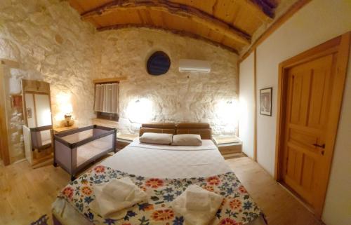 a bedroom with a large bed in a stone wall at Kandybos Eco Farm Village in Kas