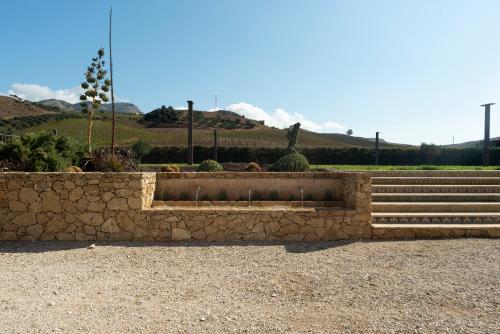 a stone retaining wall with steps and a fountain at Tenute Baglio Passofondo in Alcamo