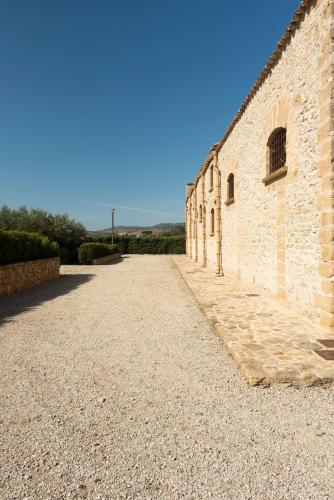a brick building with a gravel road next to it at Tenute Baglio Passofondo in Alcamo