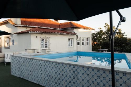a swimming pool in front of a house with an umbrella at Casa dos Chuchos in Cabanas de Viriato
