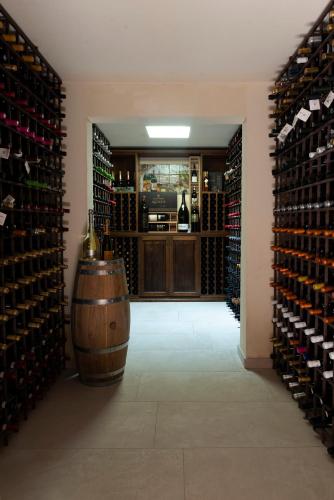 a wine cellar with a barrel and a room filled with wine bottles at Tenute Baglio Passofondo in Alcamo