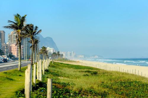 a beach with a fence and palm trees and the ocean at Grand Hyatt Rio de Janeiro in Rio de Janeiro